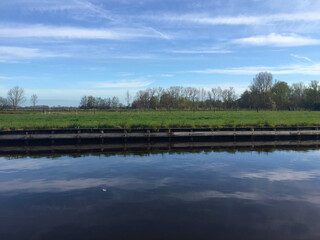 Fototapeta na wymiar the river near meadow against blue sky in the village of Giethoorn, Holland Netherlands