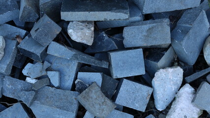 broken blocks and broken stones of different shapes and sizes in a heap of construction debris as a gray material stone background