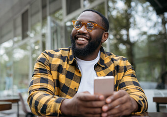 Young handsome African American man in stylish eyeglasses holding mobile phone, communication....