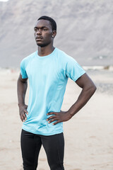 Serious ethnic athlete standing on beach