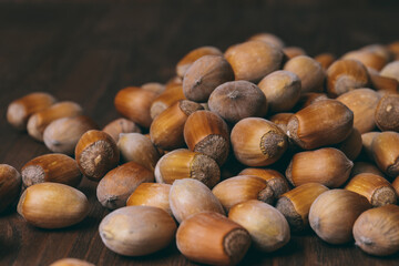 Pile of nuts. Whole nuts. Hazelnuts. Corylus avellana. Macro photo, close up, on dark wooden background.