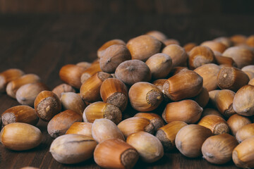 Pile of nuts. Whole nuts. Hazelnuts. Corylus avellana. Macro photo, close up, on dark wooden background.