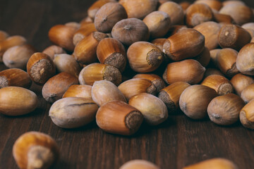Pile of nuts. Whole nuts. Hazelnuts. Corylus avellana. Macro photo, close up, on dark wooden background.