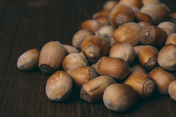 Pile of nuts. Whole nuts. Hazelnuts. Corylus avellana. Macro photo, close up, on dark wooden background.