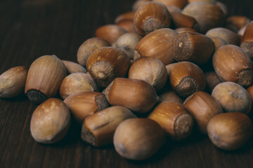 Pile of nuts. Whole nuts. Hazelnuts. Corylus avellana. Macro photo, close up, on dark wooden background.