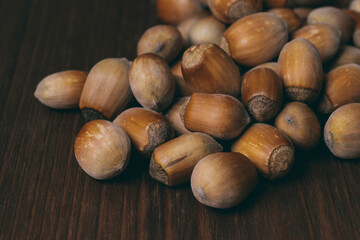 Pile of nuts. Whole nuts. Hazelnuts. Corylus avellana. Macro photo, close up, on dark wooden background.
