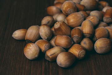 Pile of nuts. Whole nuts. Hazelnuts. Corylus avellana. Macro photo, close up, on dark wooden background.
