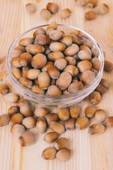 Hazelnuts in glass bowl. Whole nuts. Corylus avellana. Close up, on wooden background.