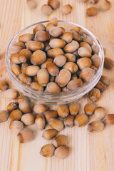 Hazelnuts in glass bowl. Whole nuts. Corylus avellana. Close up, on wooden background.