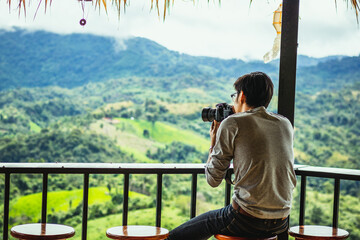 Asian male tourists take pictures of mountain landscapes after rain in northern Thailand.