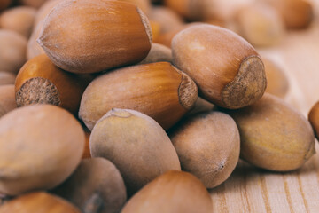 Pile of nuts. Hazelnuts. Whole nuts. Corylus avellana. Macro photo, close up, on wooden table.