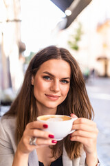 Portrait of young woman sitting in a cafe outdoor drinking coffee