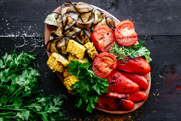 Grilled vegetables. Bell peppers, eggplant, corn, tomato on a plate with herbs