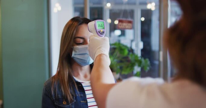 Woman wearing face mask getting her temperature measured at hair salon