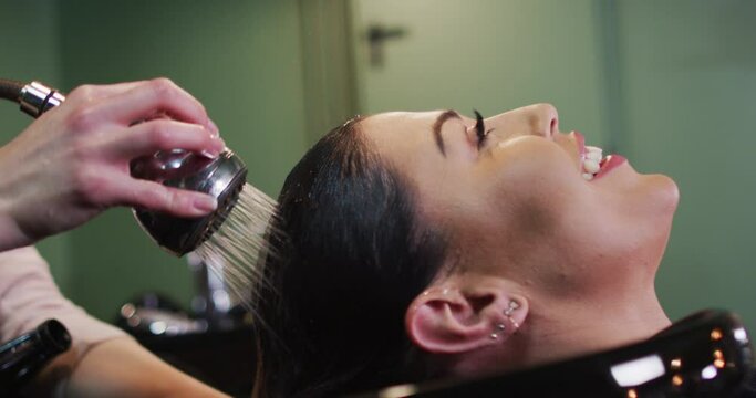 Female hairdresser washing hair of female customer at hair salon