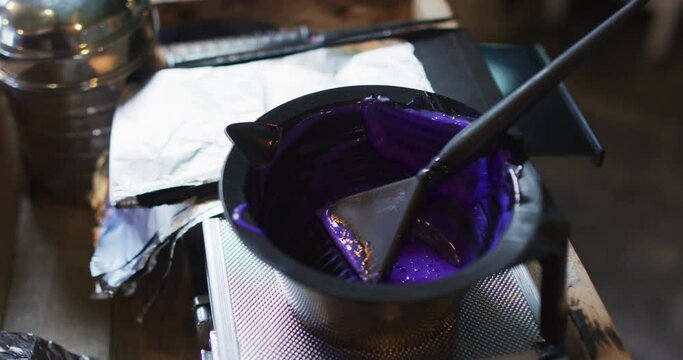 Black bowl full of purple hair dye on table at hair salon