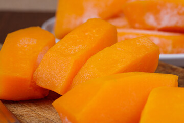 Frozen pieces of pumpkin at the wooden cutting board.