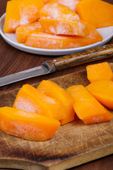 Frozen pieces of pumpkin at the wooden cutting board.