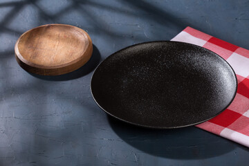 Modern black plate for serving food; photo on dark background.