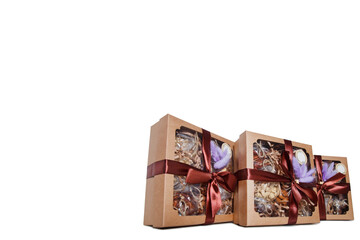 Gift box with nuts on white insulating background for holiday. Gifts Packed in box decorated with maroon ribbon and purple feathers. Gifts for Christmas, anniversary, birthday. Copy space