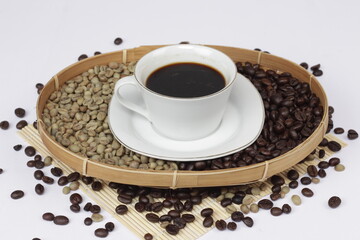 Black coffee is served in a glass cup, which is placed on top of the coffee beans. There are coffee beans that have been roasted and are still fresh beans.