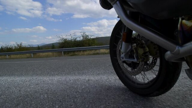 Motorcycle ridind on a road in nature. Close up wheel on a bumpy asphalt road. Recorded at 100 fps.