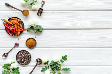 Mix of spices in metal spoons and bowls, flat lay