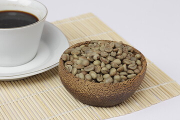 a cup of black coffee juxtaposed with fresh coffee beans on a white background.