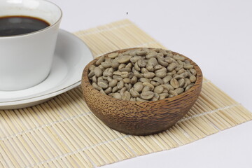 a cup of black coffee juxtaposed with fresh coffee beans on a white background.