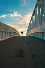 Man walking alone on the bridge. Photography symbolizes life journey, difficult choices and decisions, depression.