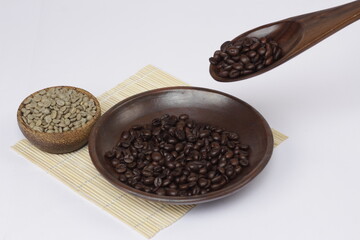 coffee beans that have been roasted and dropped from a spoon, juxtaposed against fresh coffee beans, to show the different color of the coffee beans.