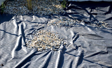 delivery of gray river pebbles like mulch to flower beds in the garden using a wheelbarow from the...