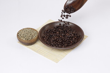coffee beans that have been roasted and dropped from a spoon, juxtaposed against fresh coffee beans, to show the different color of the coffee beans.