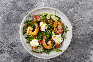 Salad with shrimp, arugula ,cucumber and onion on a white plate