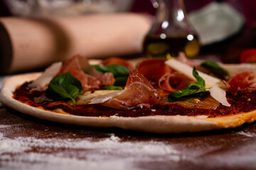 Handmade pizza parma mozzarella, ham and parmesan close up on the table with flour and decoration, very tasty