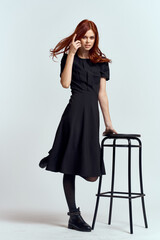 Fototapeta premium woman high chair indoors full length black dress red hair model boots