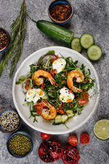 Salad with shrimp, arugula ,cucumber and onion on a white plate