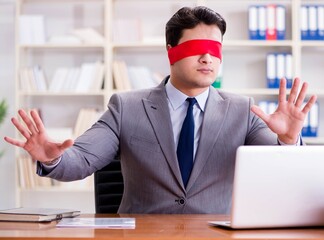 Blindfold businessman sitting at desk in office