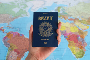 Hand holding a Brazilian passport with a map background