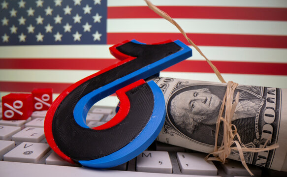 A 3D printed Tik Tok logo and percentage boxes, dollar banknotes and keyboard are seen in front of U.S. flag in this illustration