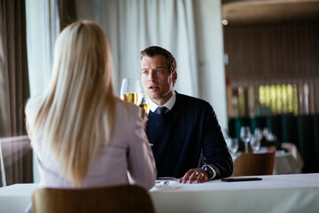Handsome businessman dressed in the suit drinking wine. Businessman enjoying in the restaurant..