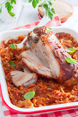 Baked pork shank with enamelled cabbage on a wooden table, selective focus