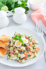 Salad with red fish, fresh cucumbers and herbs, an egg on a white plate with white bread toasts, selective focus