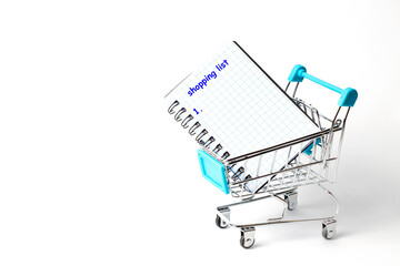 Notepad with the inscription shopping list in a grocery cart from the supermarket on a white...