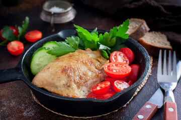 Fried chicken thighs in a portioned cast iron pan, selective focus