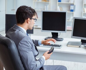 Businessman sitting in front of many screens