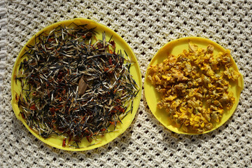 Dried flower seeds and dried yellow flowers, in a round bowl, for herbal infusion.