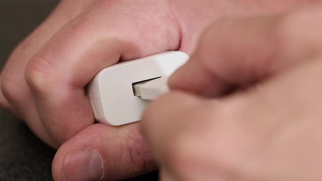 Hand plug usb charger adapter and wire into wall socket. close up