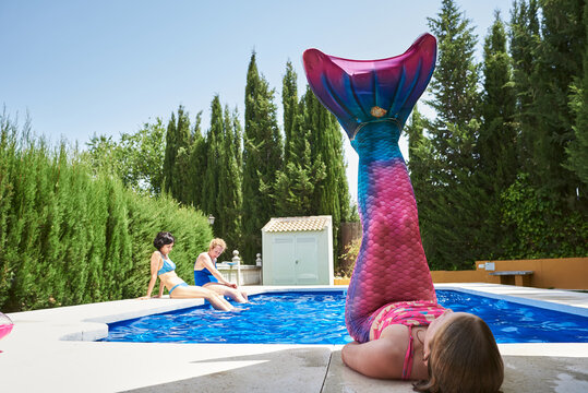 Little girl with mermaid tail in a swimming pool.
