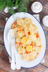 Baked potatoes with carrots in the oven on a white dish, selective focus
